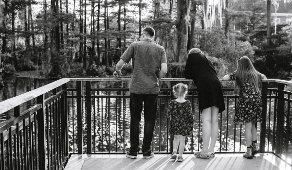 One man, woman, and two children, from behind, as they look into a swamp