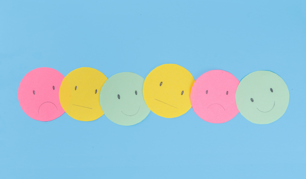 Colorful faces with a variety of emotional expressions on a blue background